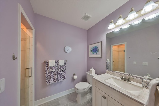 bathroom with tile patterned floors, vanity, toilet, and a shower with shower door