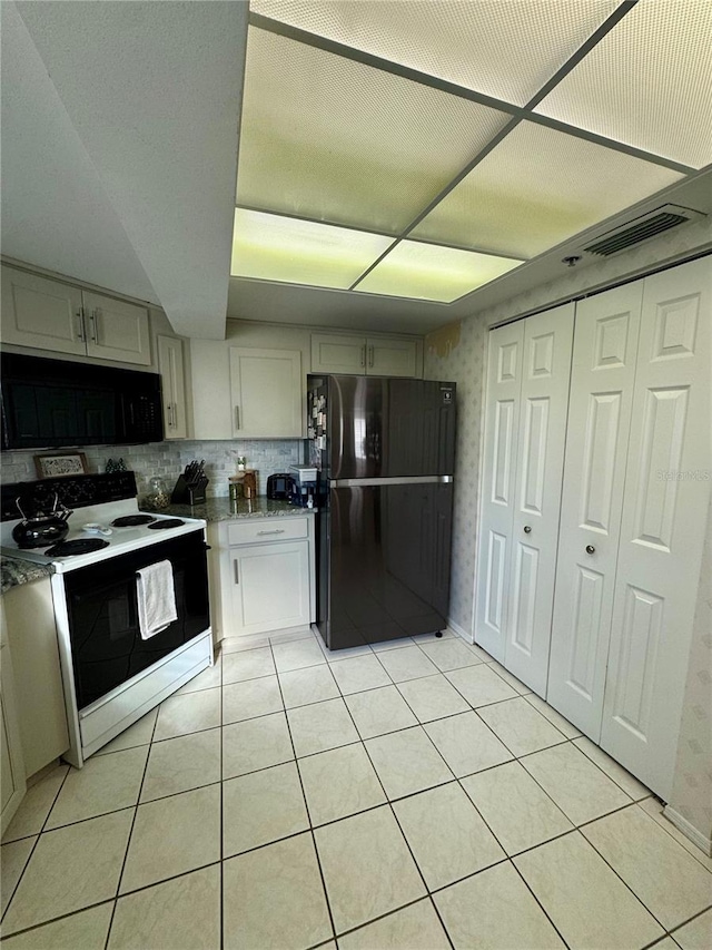 kitchen featuring light stone countertops, light tile patterned floors, decorative backsplash, and black appliances