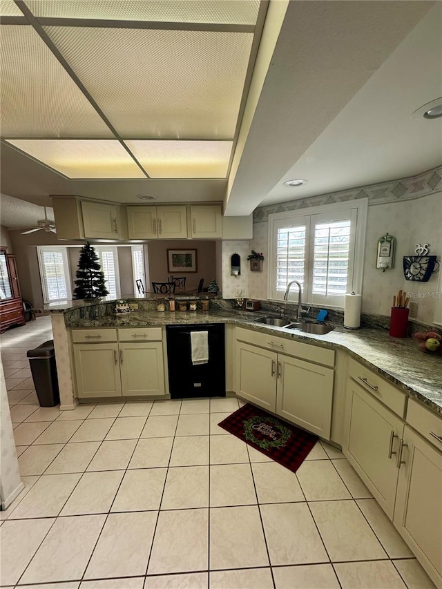 kitchen featuring dishwasher, sink, light tile patterned floors, and cream cabinetry