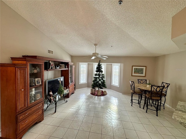 dining area featuring lofted ceiling, light tile patterned floors, a textured ceiling, and ceiling fan