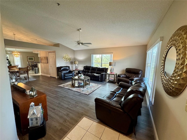 living room featuring ceiling fan, a textured ceiling, vaulted ceiling, and wood-type flooring