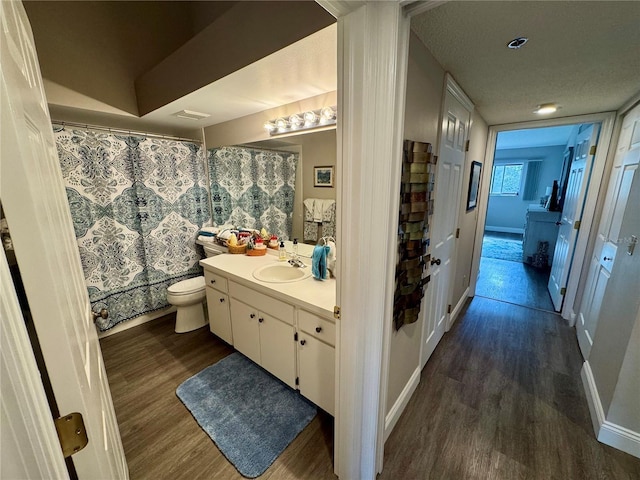 bathroom with vanity, toilet, hardwood / wood-style floors, and a textured ceiling