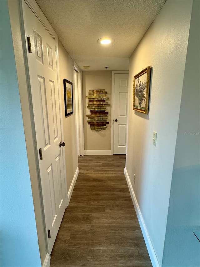 hallway featuring dark hardwood / wood-style floors and a textured ceiling