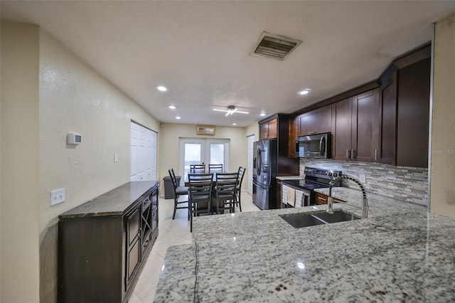 kitchen with sink, french doors, light stone counters, backsplash, and appliances with stainless steel finishes