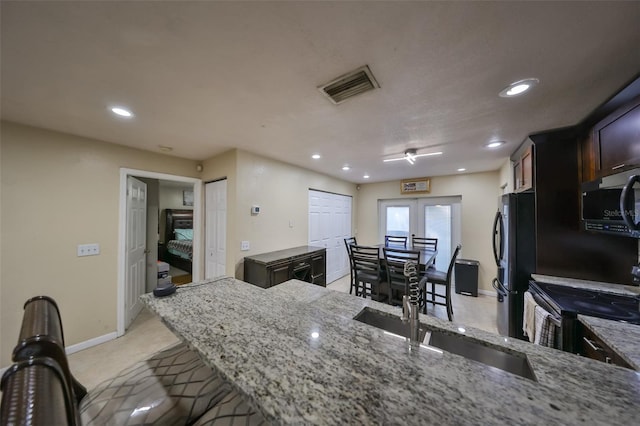 kitchen with french doors, light stone counters, black electric range oven, kitchen peninsula, and fridge