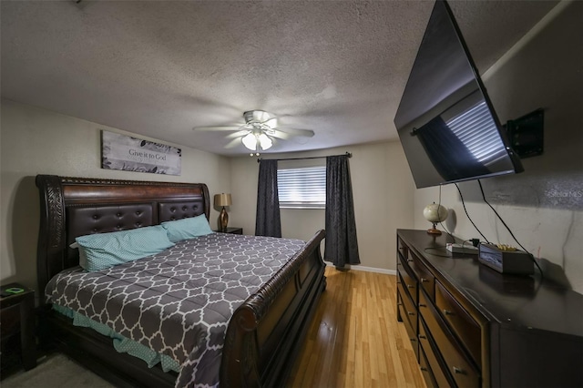 bedroom featuring ceiling fan, light hardwood / wood-style floors, and a textured ceiling