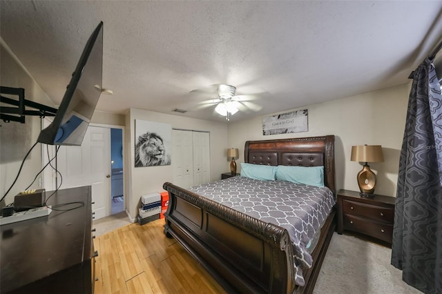 bedroom with ceiling fan, light wood-type flooring, a textured ceiling, and a closet