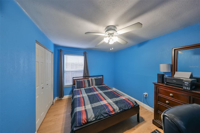 bedroom featuring a closet, ceiling fan, light hardwood / wood-style flooring, and a textured ceiling