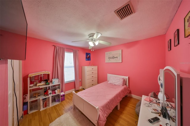 bedroom featuring ceiling fan, light hardwood / wood-style floors, and a textured ceiling