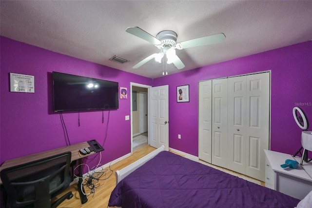 bedroom featuring a textured ceiling, light wood-type flooring, a closet, and ceiling fan