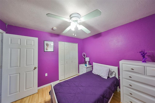 bedroom featuring ceiling fan, light hardwood / wood-style floors, a textured ceiling, and a closet