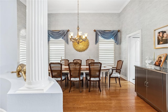 dining area featuring a chandelier, wood-type flooring, decorative columns, and ornamental molding