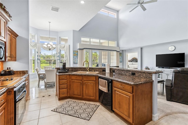 kitchen with a high ceiling, black appliances, dark stone countertops, and sink