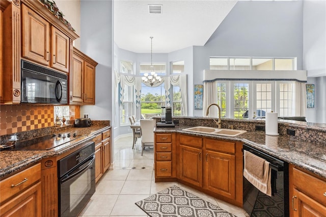 kitchen featuring a wealth of natural light, sink, black appliances, and a notable chandelier