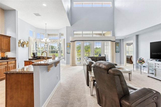 kitchen with a breakfast bar, a high ceiling, light carpet, and hanging light fixtures