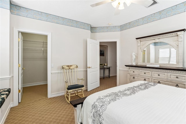 bedroom with ceiling fan, a spacious closet, light carpet, and a closet