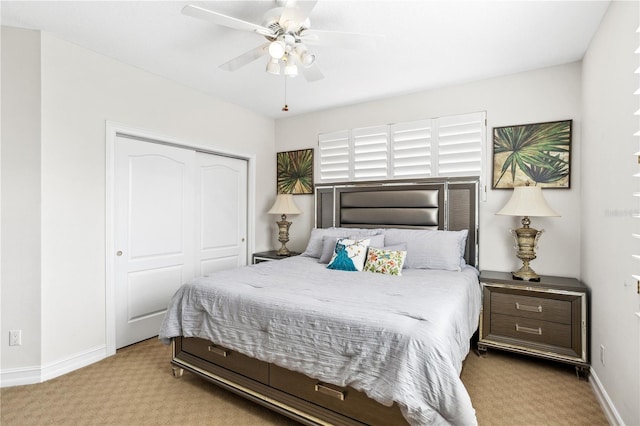 bedroom with ceiling fan, light colored carpet, and a closet