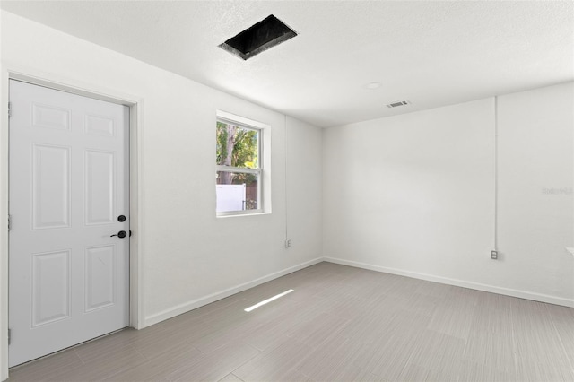 spare room featuring light wood-type flooring and a textured ceiling