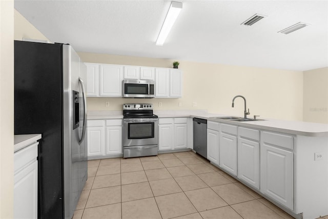 kitchen featuring kitchen peninsula, stainless steel appliances, sink, white cabinets, and light tile patterned flooring