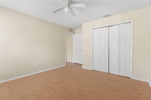 unfurnished bedroom featuring ceiling fan, light wood-type flooring, and a closet