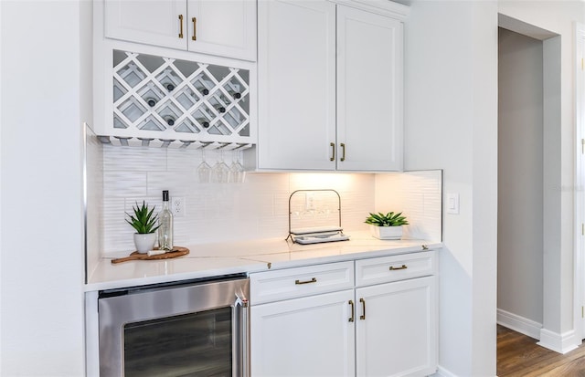 bar with hardwood / wood-style floors, white cabinets, light stone countertops, tasteful backsplash, and beverage cooler