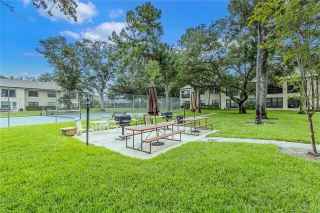 view of home's community with a lawn and tennis court