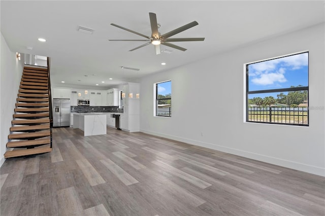 unfurnished living room with ceiling fan and light wood-type flooring