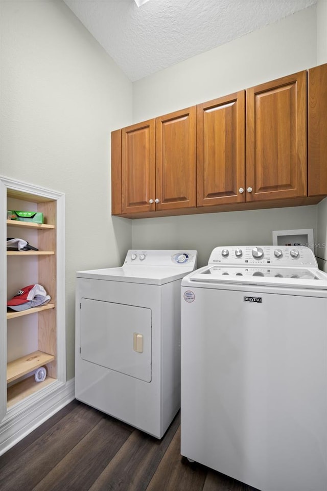 laundry area featuring cabinets, dark hardwood / wood-style flooring, a textured ceiling, and washer and clothes dryer