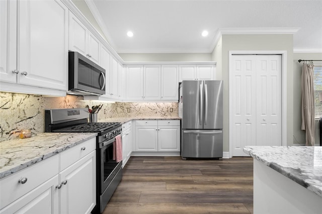 kitchen featuring white cabinetry, appliances with stainless steel finishes, crown molding, and light stone counters