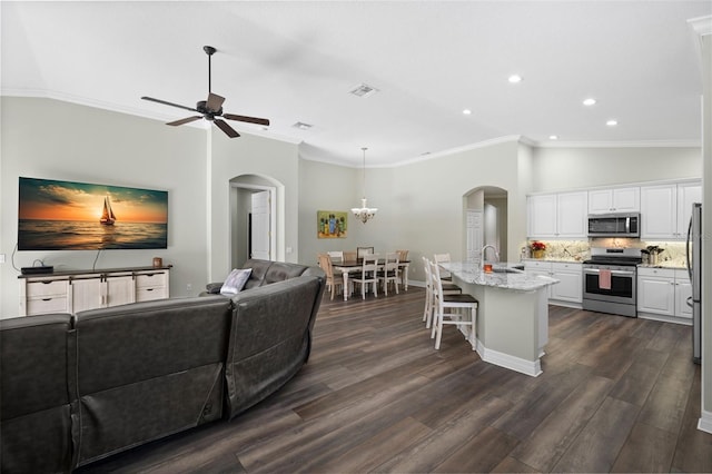 living room with lofted ceiling, sink, ornamental molding, ceiling fan, and dark wood-type flooring