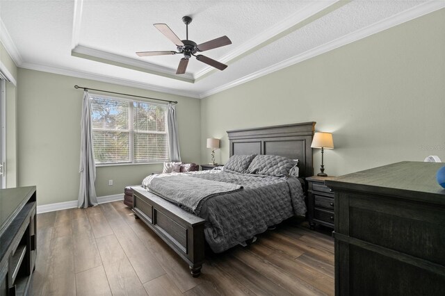 bedroom with crown molding, ceiling fan, dark hardwood / wood-style floors, a textured ceiling, and a raised ceiling