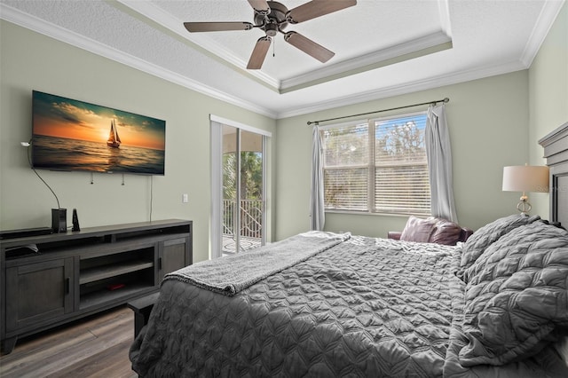 bedroom with dark hardwood / wood-style floors, ornamental molding, access to exterior, a tray ceiling, and a textured ceiling