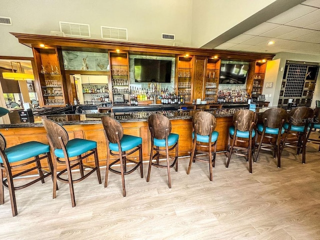 bar with a drop ceiling and light wood-type flooring