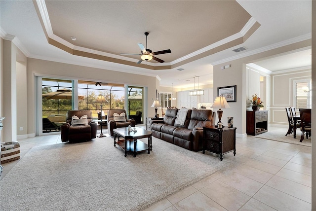 tiled living room with a raised ceiling, ceiling fan, and ornamental molding