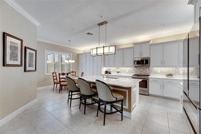 kitchen with a center island with sink, pendant lighting, ornamental molding, and appliances with stainless steel finishes