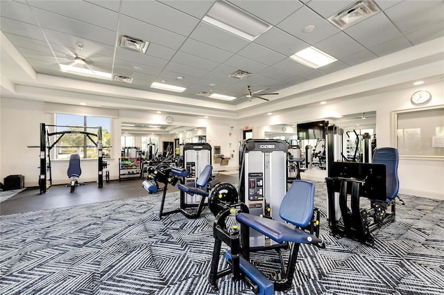 workout area with a paneled ceiling, ceiling fan, and a tray ceiling