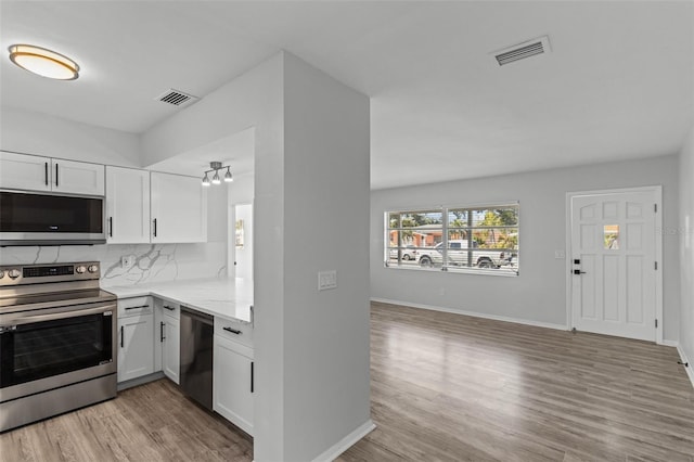 kitchen featuring white cabinets, stainless steel appliances, tasteful backsplash, and light hardwood / wood-style floors