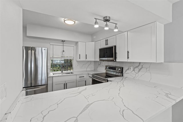 kitchen featuring backsplash, sink, light stone countertops, white cabinetry, and stainless steel appliances