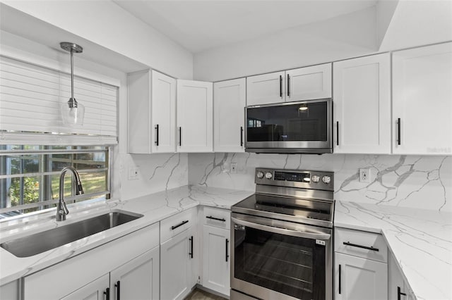 kitchen featuring appliances with stainless steel finishes, tasteful backsplash, sink, pendant lighting, and white cabinetry