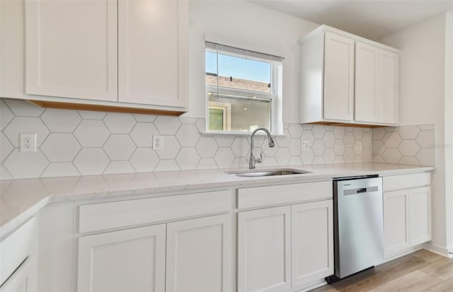 kitchen featuring backsplash, white cabinetry, sink, and stainless steel dishwasher