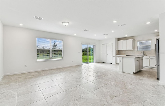 10328 Cross River Trl, Parrish, FL 34219 - unfurnished living room with visible vents, recessed lighting, baseboards, and a sink