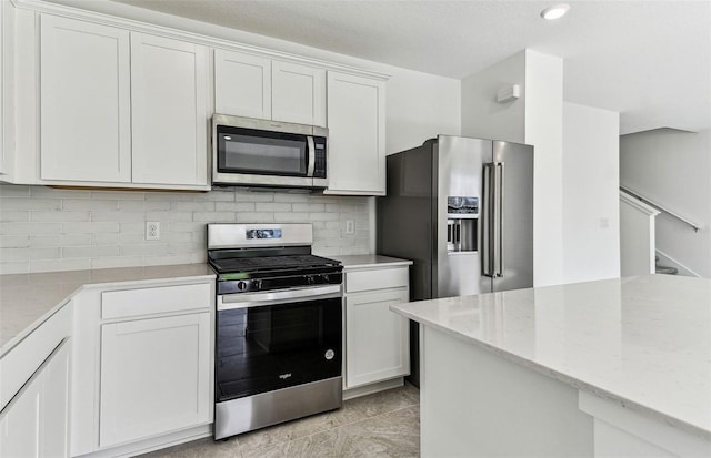 10328 Cross River Trl, Parrish, FL 34219 - kitchen with light stone counters, white cabinetry, appliances with stainless steel finishes, and tasteful backsplash