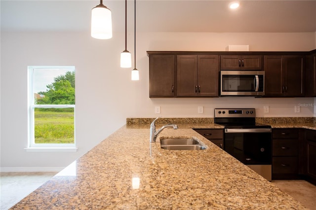 kitchen featuring pendant lighting, sink, light stone countertops, and stainless steel appliances