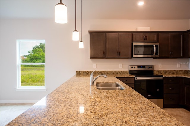 449 Grant Blvd, Lehigh Acres, FL 33974 - kitchen featuring appliances with stainless steel finishes, a sink, dark brown cabinetry, light stone counters, and hanging light fixtures