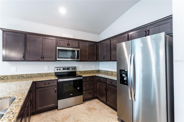 kitchen with dark brown cabinetry, light stone countertops, vaulted ceiling, and appliances with stainless steel finishes