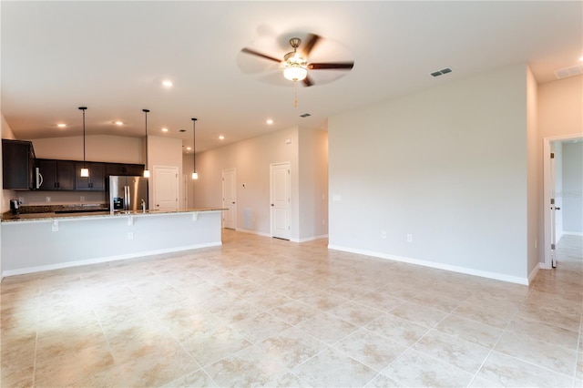 kitchen with hanging light fixtures, vaulted ceiling, ceiling fan, light stone counters, and stainless steel fridge with ice dispenser