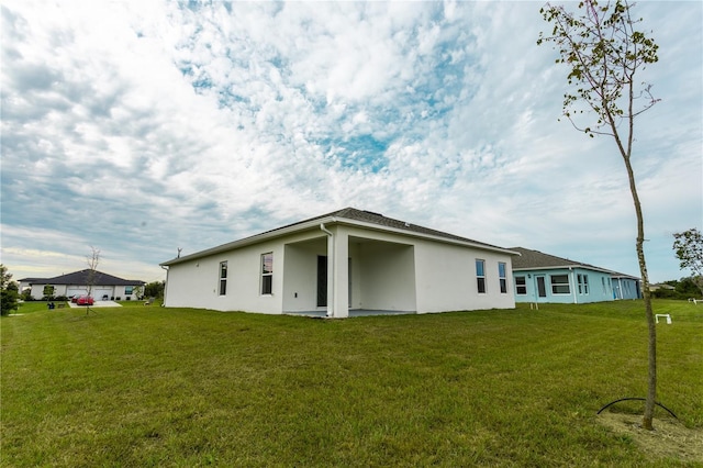 449 Grant Blvd, Lehigh Acres, FL 33974 - rear view of property featuring stucco siding and a lawn