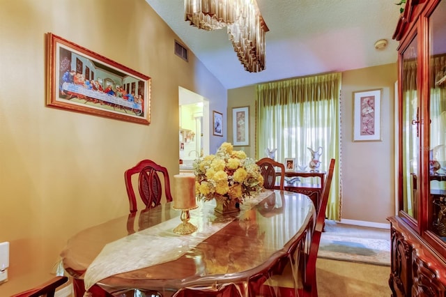 dining room with a notable chandelier, light colored carpet, lofted ceiling, and a textured ceiling