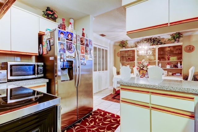 kitchen featuring a notable chandelier, white cabinetry, stainless steel appliances, and light tile patterned floors