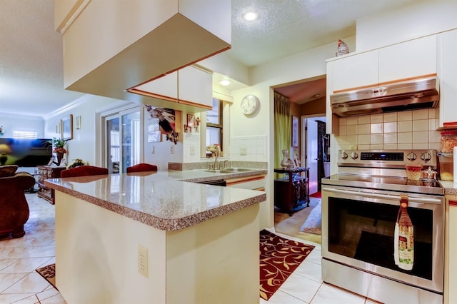 kitchen featuring kitchen peninsula, decorative backsplash, a textured ceiling, electric range, and white cabinetry